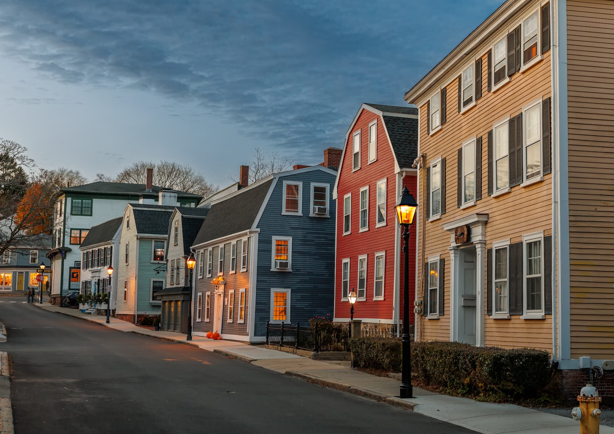 Historic Old Town Marblehead at dusk, with lantern-lit streets and colonial buildings